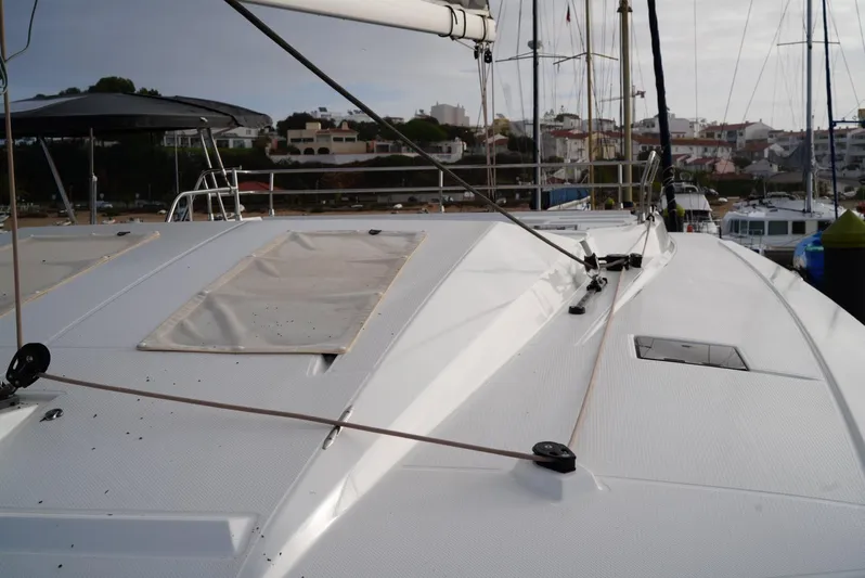 Elysium 1 Yacht Photos Pics 2022 Fountaine Pajot Elba Quatour catamaran deck with rigging and coastal background.