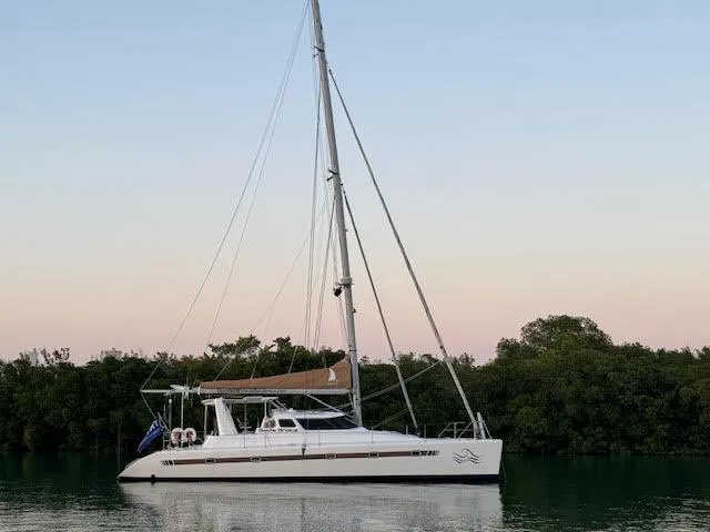 Gods Grace Yacht Photos Pics Voyage Yachts 500 catamaran, 2010 model, anchored near lush greenery at sunset.