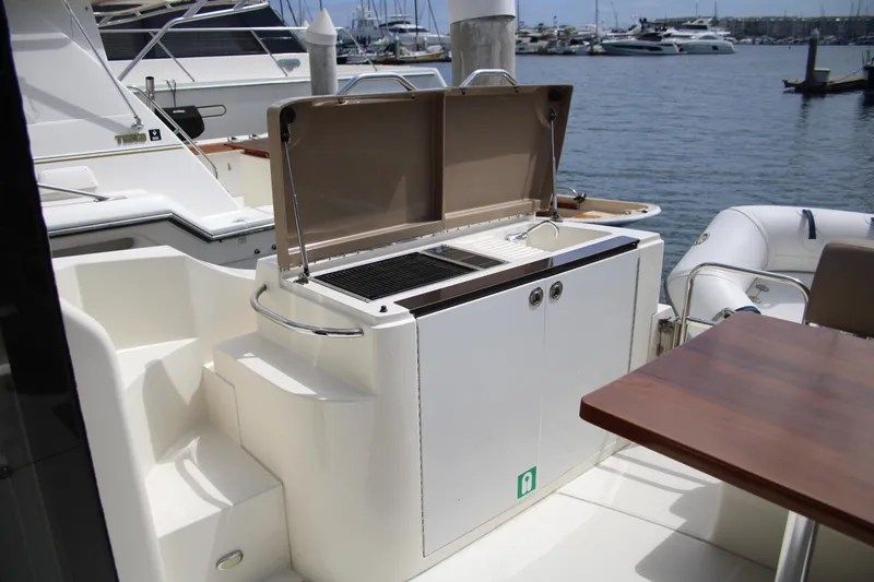 Skywalker Yacht Photos Pics Outdoor yacht kitchen with grill and sink, docked at marina with boats in background.