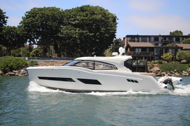 Skywalker Yacht Photos Pics A luxury yacht cruising near a residential area with lush greenery.