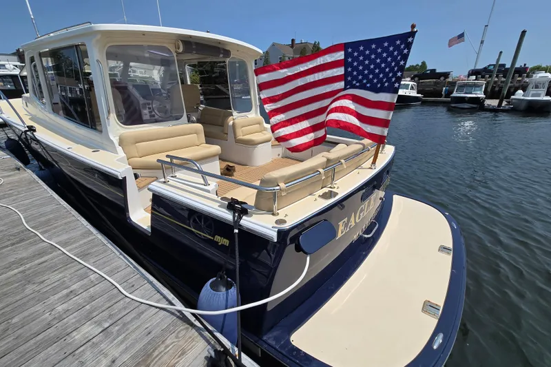 Eagle Wing Yacht Photos Pics 2017 MJM 40z Downeast boat docked, featuring American flag and spacious seating.