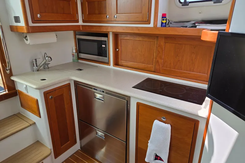 Eagle Wing Yacht Photos Pics 2017 MJM 40z Downeast yacht kitchen with wood cabinets, sink, microwave, and stovetop.