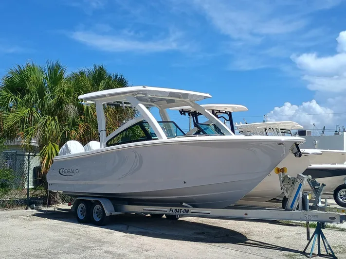 257-155 Yacht Photos Pics 2025 Robalo R257 Dual Console boat on trailer, parked outdoors under blue sky.