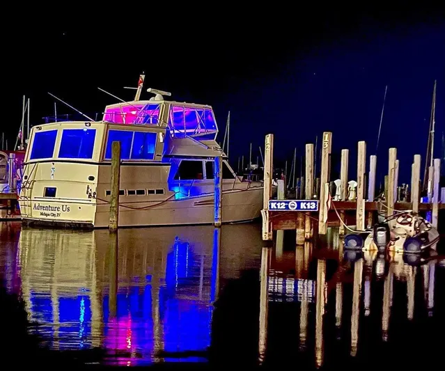 Sunshine State Yacht Photos Pics Viking 48 Motoryacht 1987 docked at night, illuminated in blue and pink.