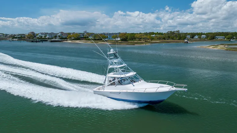 Life Is Good Yacht Photos Pics A 2013 Viking 42 yacht cruising swiftly on a scenic waterway under a partly cloudy sky.