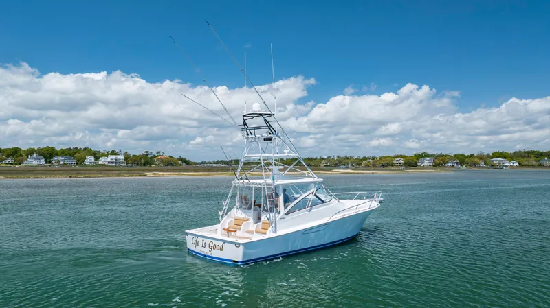 Life Is Good Yacht Photos Pics 2013 Viking 42 boat cruising on a calm, scenic waterway under a partly cloudy sky.