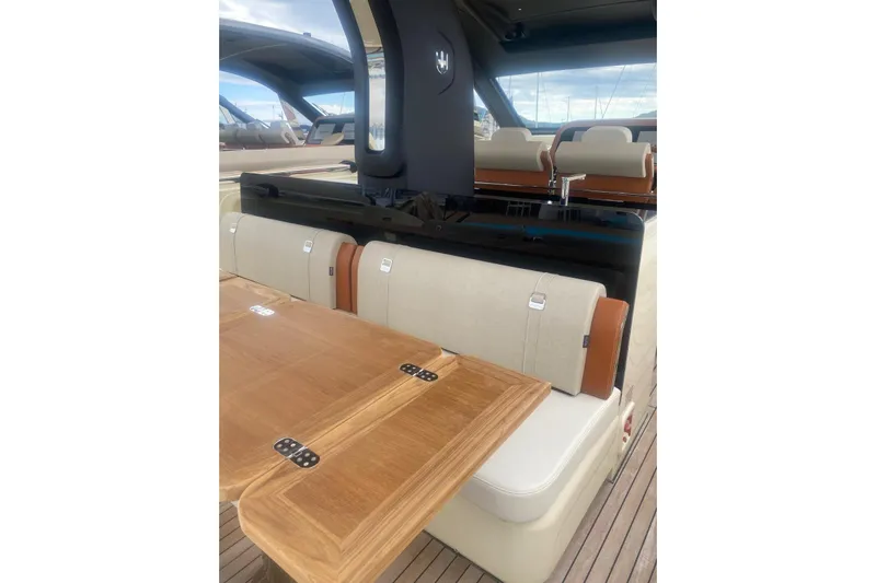  Yacht Photos Pics Interior of Invictus TT 420 yacht, 2024 model, featuring wooden table and cushioned seats.
