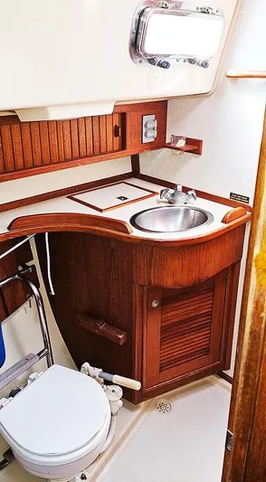 Kewaydin Yacht Photos Pics 1997 Island Packet 40 yacht bathroom with wooden cabinetry and stainless steel sink.