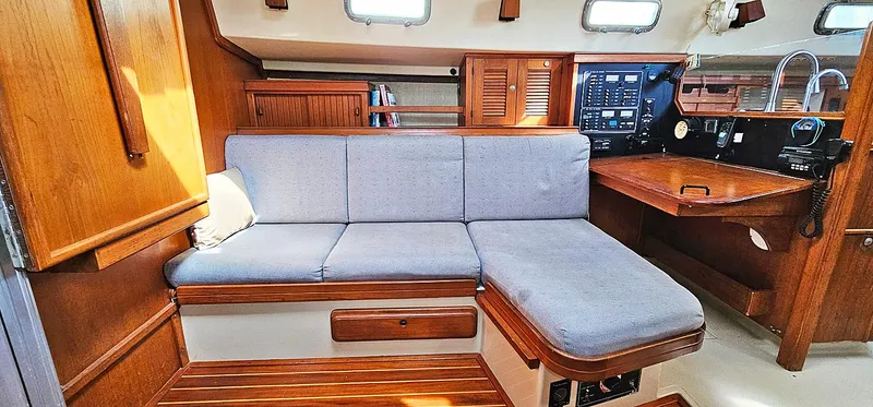 Kewaydin Yacht Photos Pics Interior of 1997 Island Packet 40 sailboat with wooden cabinetry and blue cushioned seating.