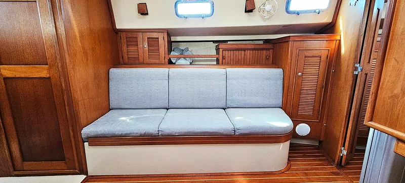 Kewaydin Yacht Photos Pics Interior of 1997 Island Packet 40 sailboat with wooden cabinetry and cushioned seating.