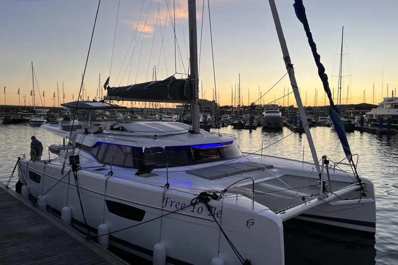 Free To Be Yacht Photos Pics 2022 Fountaine Pajot Elba 45 Catamaran docked at sunset in a marina.