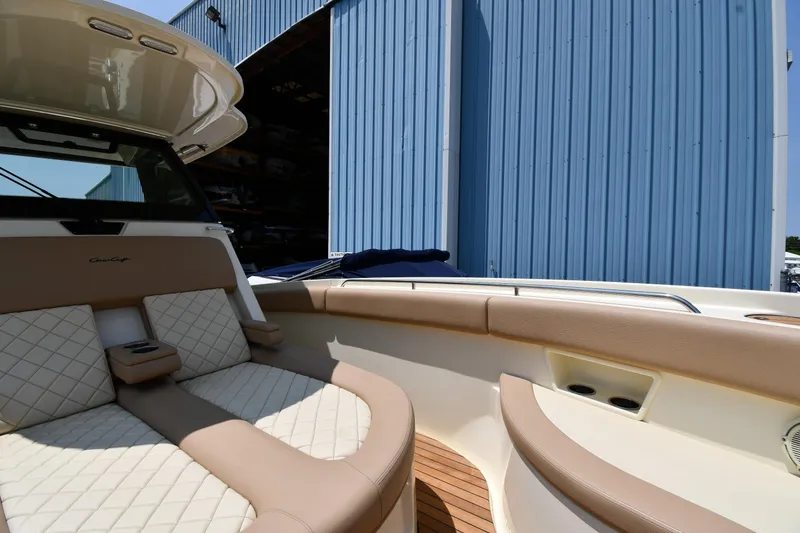  Yacht Photos Pics 2024 Chris-Craft Catalina 30 boat with luxurious seating near a blue warehouse.