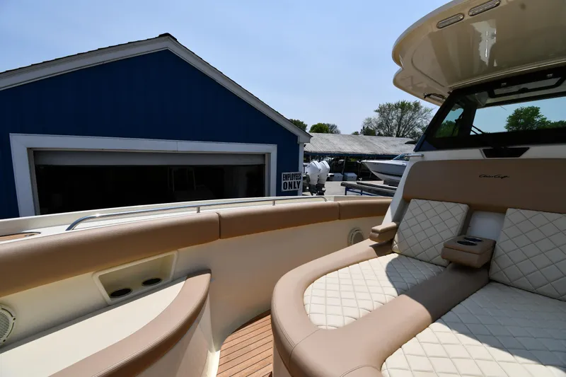  Yacht Photos Pics 2024 Chris-Craft Catalina 30 boat with luxurious seating, docked near a blue building.