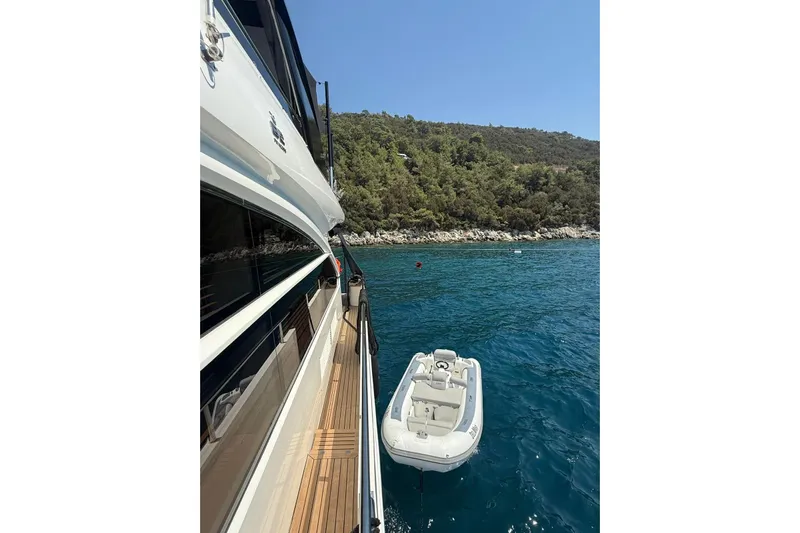  Yacht Photos Pics 2014 Princess Flybridge 82 Motor Yacht on serene blue waters near a lush coastline.