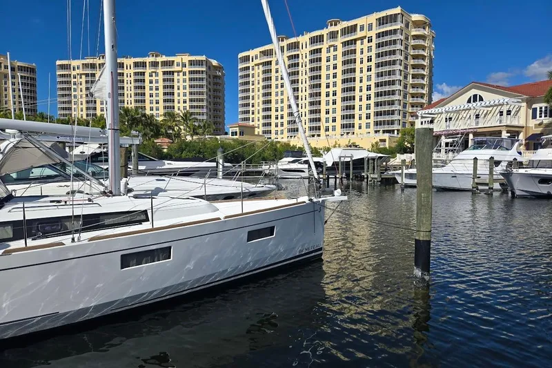 Bluebird Yacht Photos Pics 2023 Beneteau Oceanis 38.1 yacht docked in marina with tall buildings in background.