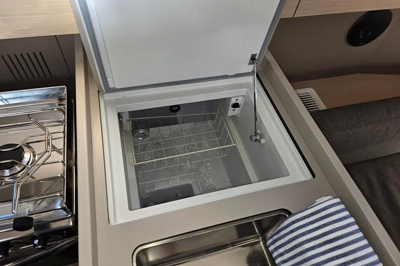 Bluebird Yacht Photos Pics Beneteau Oceanis 38.1 yacht kitchen with open fridge, stove, and striped towel, 2023 model.