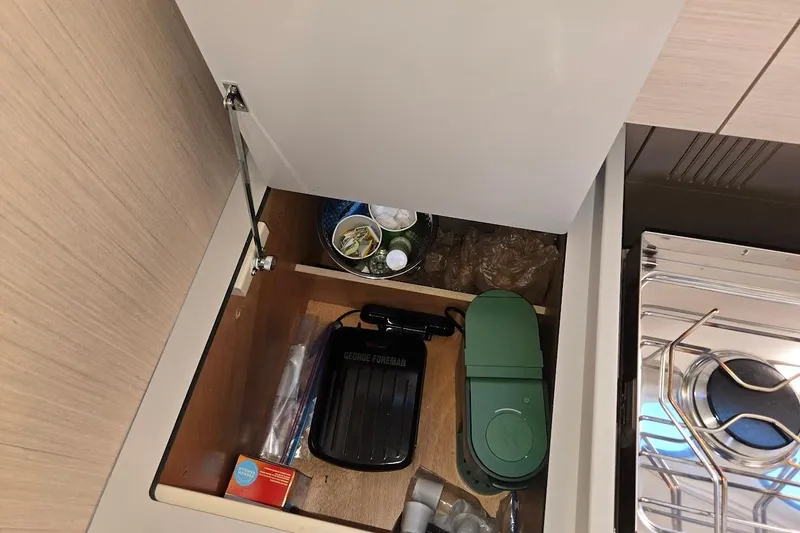Bluebird Yacht Photos Pics Storage compartment in 2023 Beneteau Oceanis 38.1 yacht kitchen with various items.