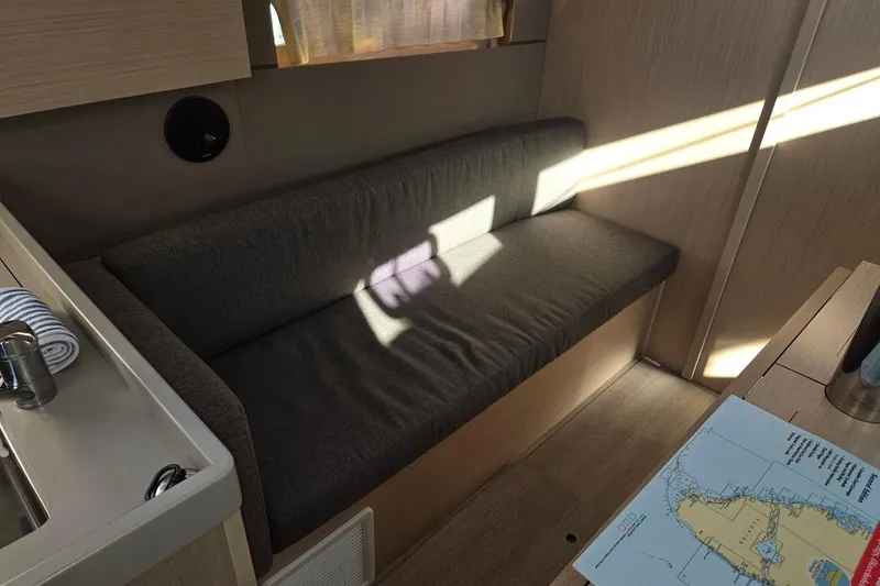 Bluebird Yacht Photos Pics 2023 Beneteau Oceanis 38.1 interior with sofa, map, and sunlight.