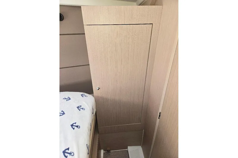 Bluebird Yacht Photos Pics Interior cabin of 2023 Beneteau Oceanis 38.1 yacht with wooden paneling and anchor-patterned bedding.