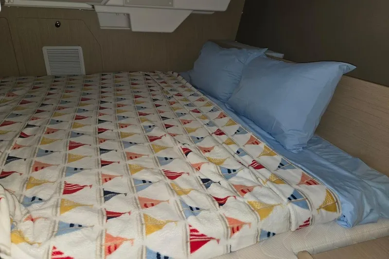 Bluebird Yacht Photos Pics Cozy cabin bed in 2023 Beneteau Oceanis 38.1 yacht with colorful sailboat-patterned blanket.