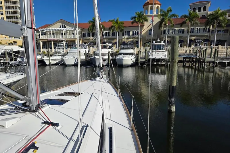 Bluebird Yacht Photos Pics 2023 Beneteau Oceanis 38.1 sailboat docked at a marina with palm trees and buildings.