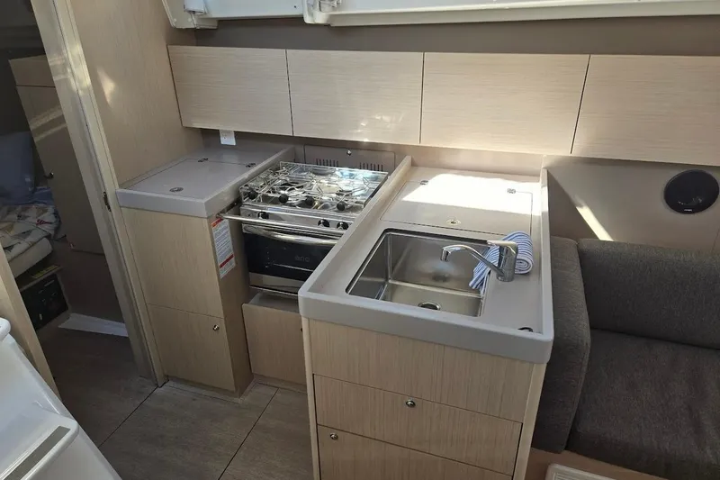 Bluebird Yacht Photos Pics 2023 Beneteau Oceanis 38.1 yacht interior kitchen with stove, sink, and cabinets.