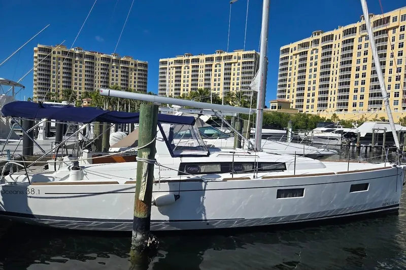 Bluebird Yacht Photos Pics 2023 Beneteau Oceanis 38.1 sailboat docked at marina with tall buildings in background.