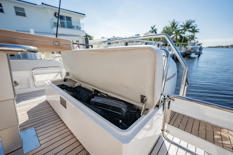  Yacht Photos Pics 2024 Schaefer V33 boat with open storage compartment, docked by waterfront homes.