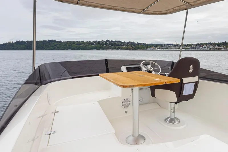 Cheers Yacht Photos Pics 2019 Beneteau Swift Trawler 35 helm with wooden table, overlooking serene waters.