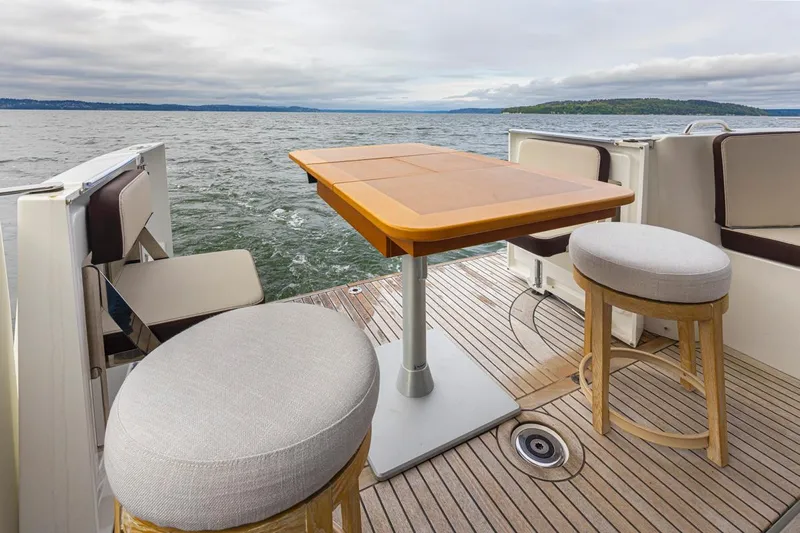 Cheers Yacht Photos Pics 2019 Beneteau Swift Trawler 35 deck with seating and table, overlooking serene waters.