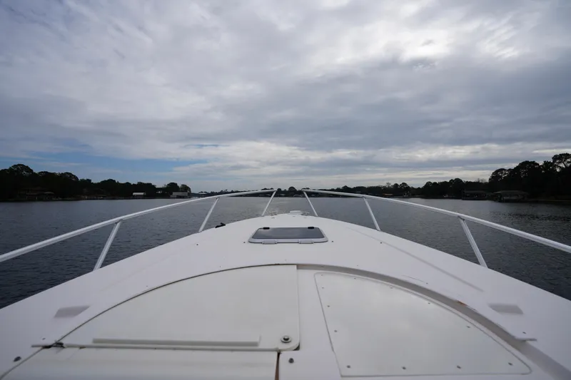  Yacht Photos Pics 1999 Intrepid 366 boat cruising on a calm lake under a cloudy sky.