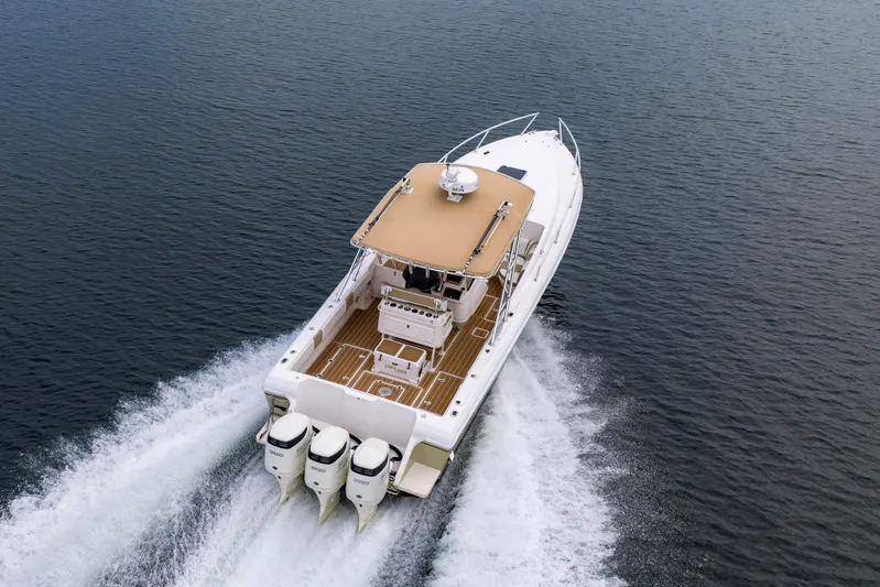  Yacht Photos Pics 1999 Intrepid 366 boat cruising on open water, rear view with triple engines.