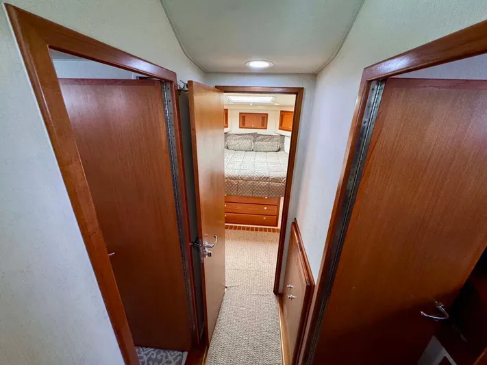 Bill Slayer Yacht Photos Pics Interior hallway of 2002 Cabo 47 Flybridge Sportfisher, leading to a cozy bedroom.
