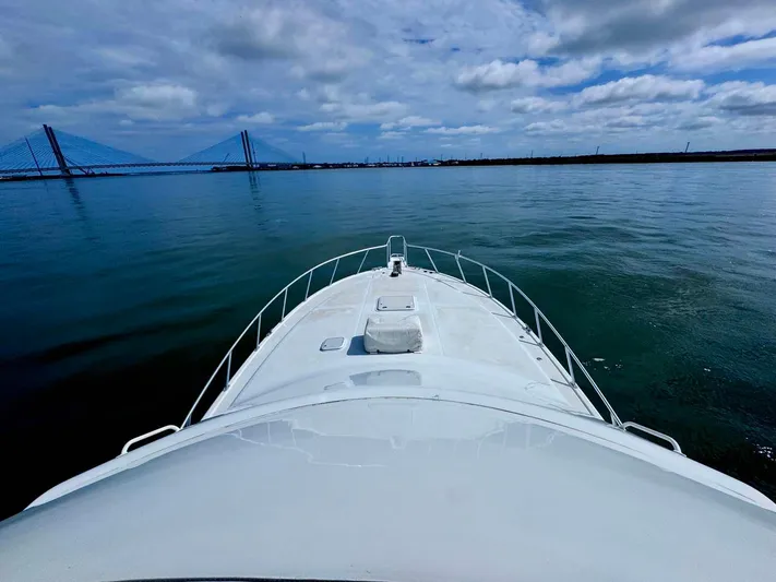 Bill Slayer Yacht Photos Pics 2002 Cabo 47 Flybridge Sportfisher on calm water with bridge in background.