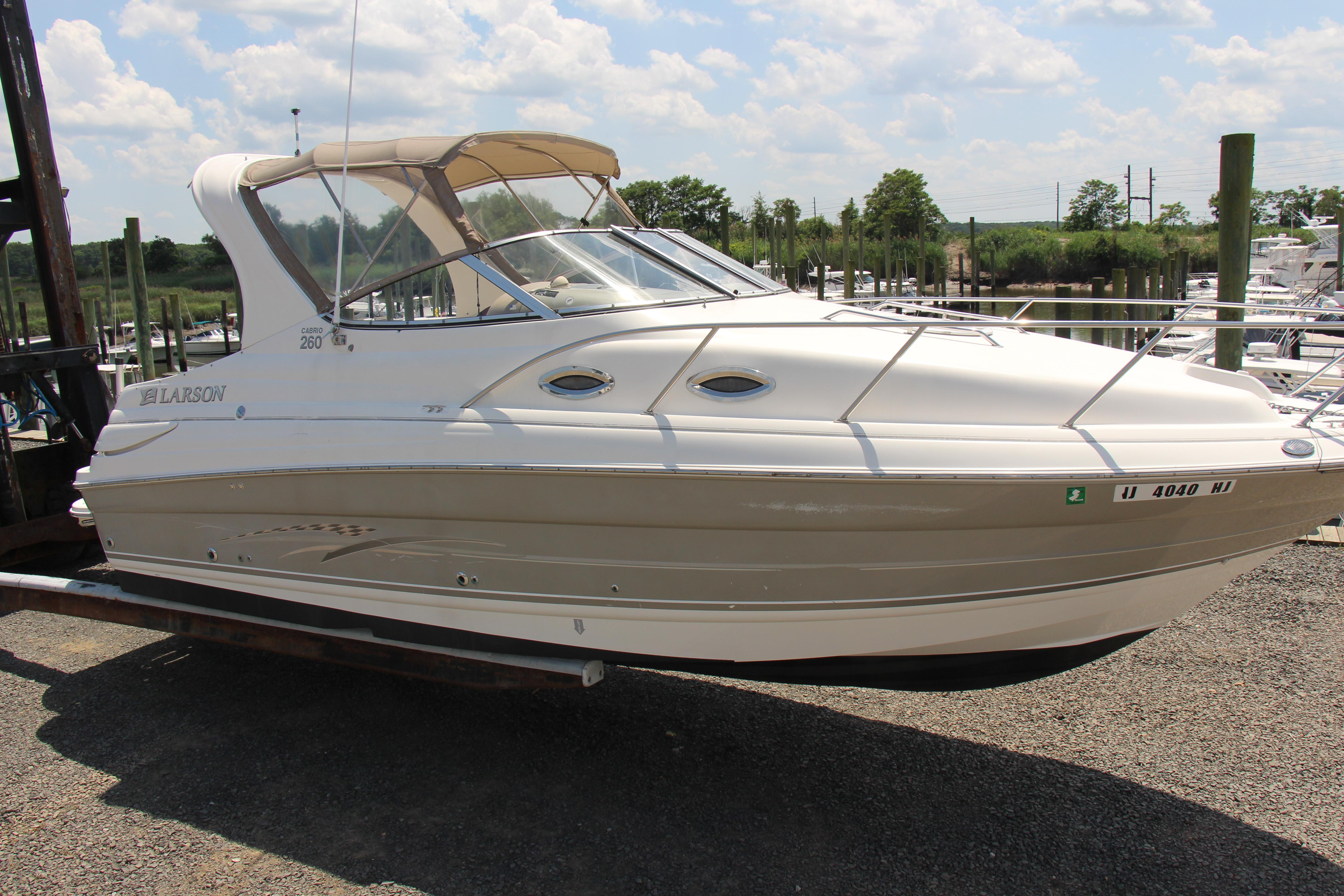 2008 Larson Cabrio 260 boat on a trailer at a marina under a partly cloudy sky.