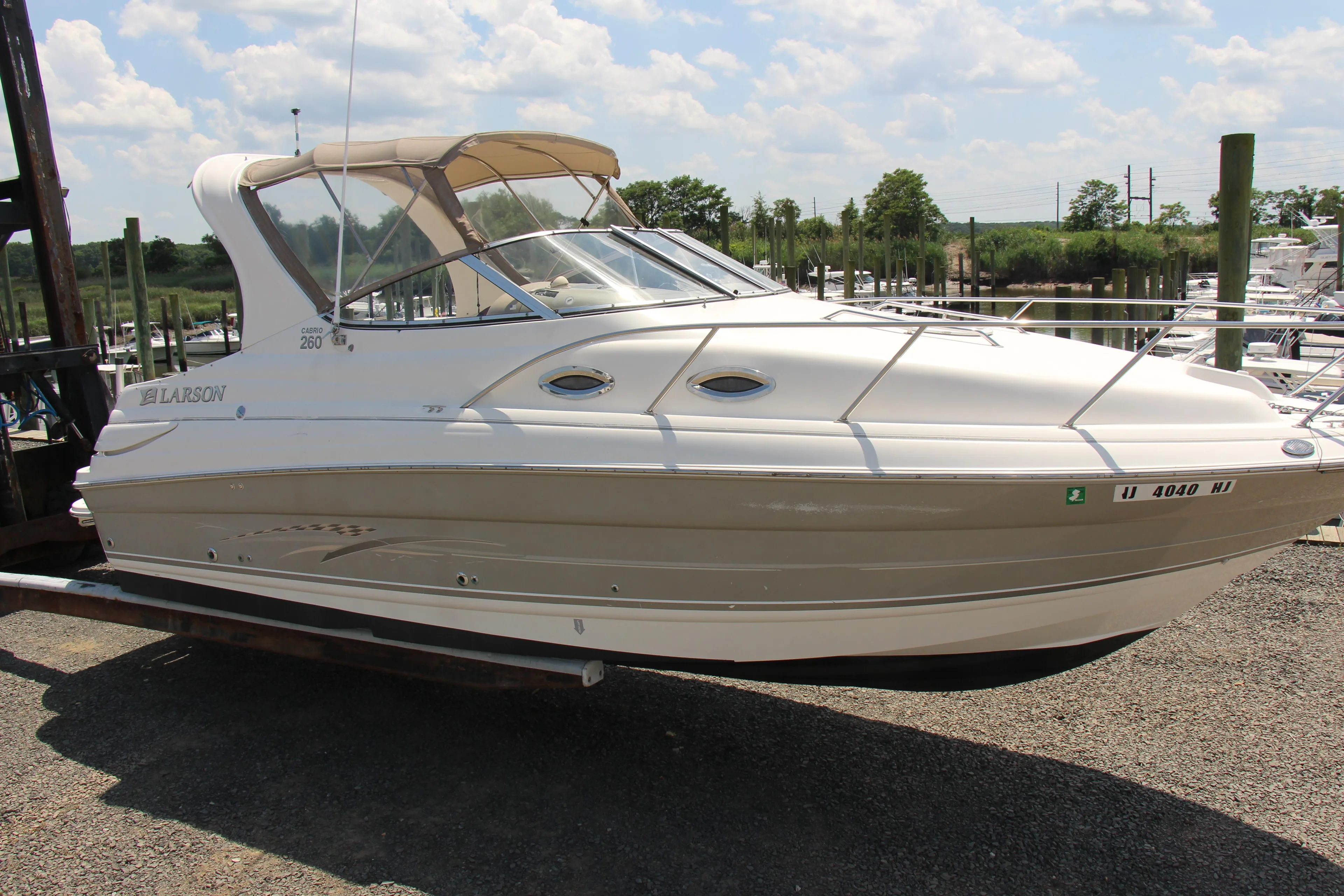 2008 Larson Cabrio 260 boat on a trailer at a marina under a partly cloudy sky.