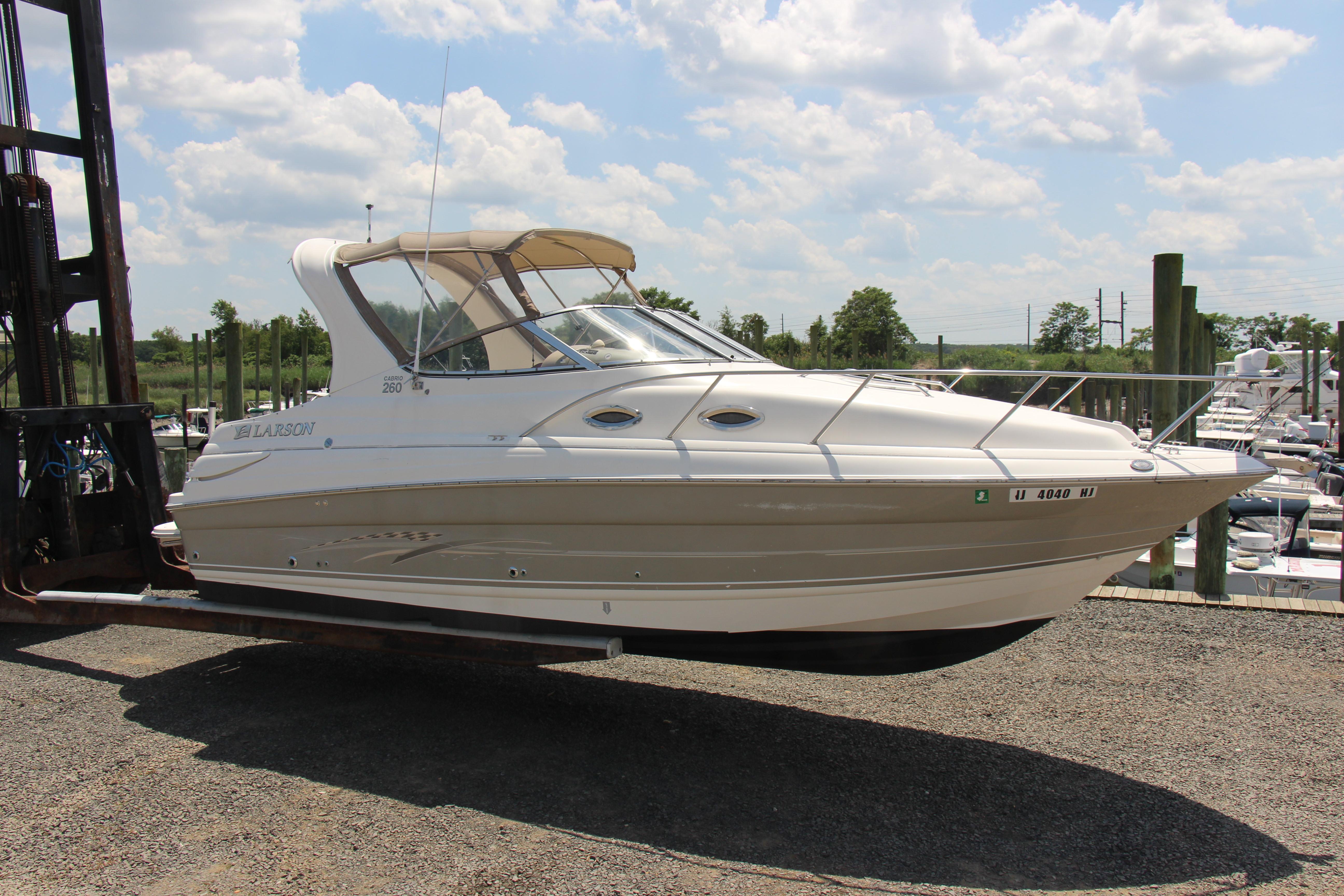 2008 Larson Cabrio 260 boat lifted on a forklift, sunny day, marina background.