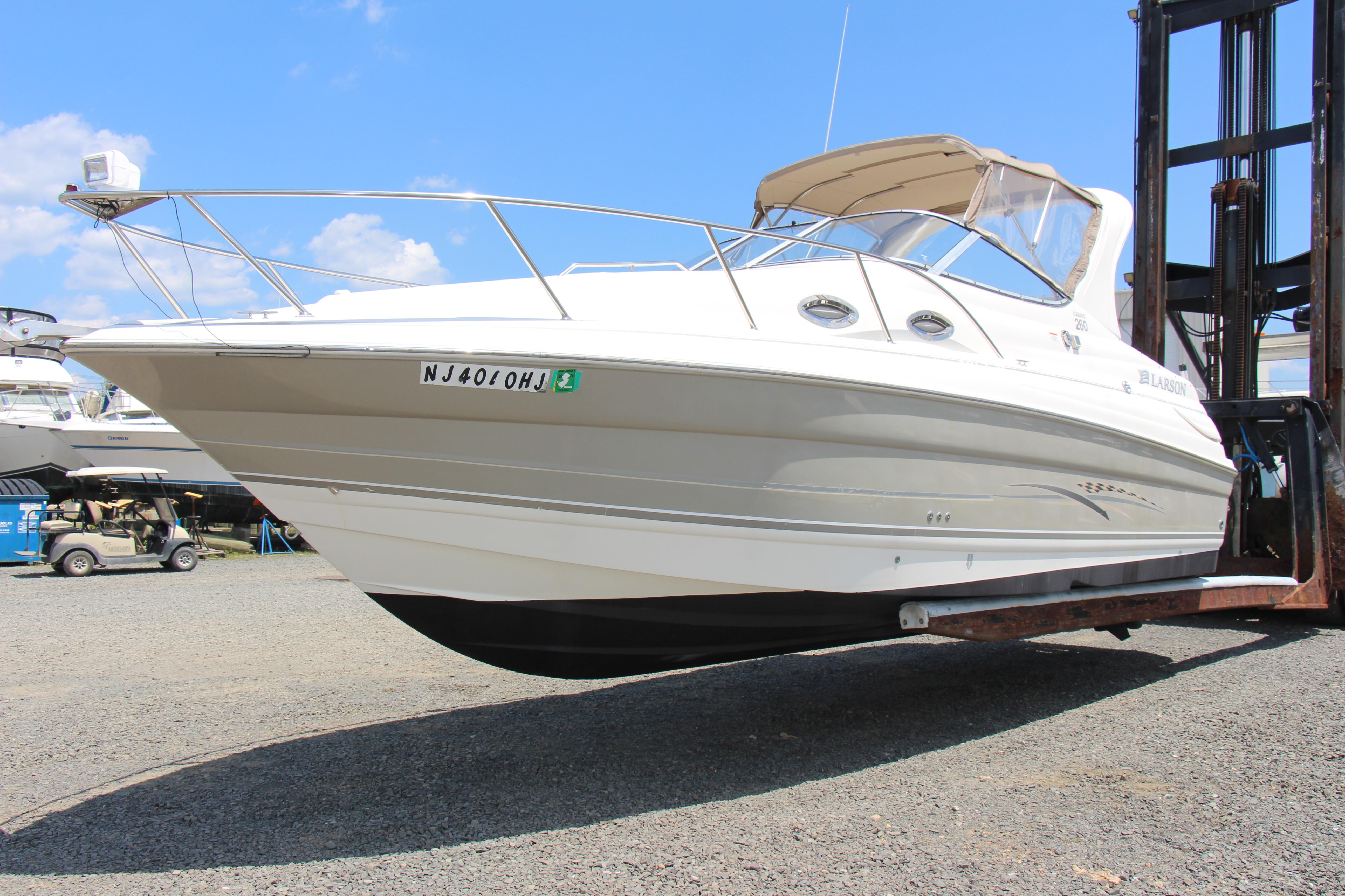 2008 Larson Cabrio 260 boat on forklift, displayed outdoors under blue sky.