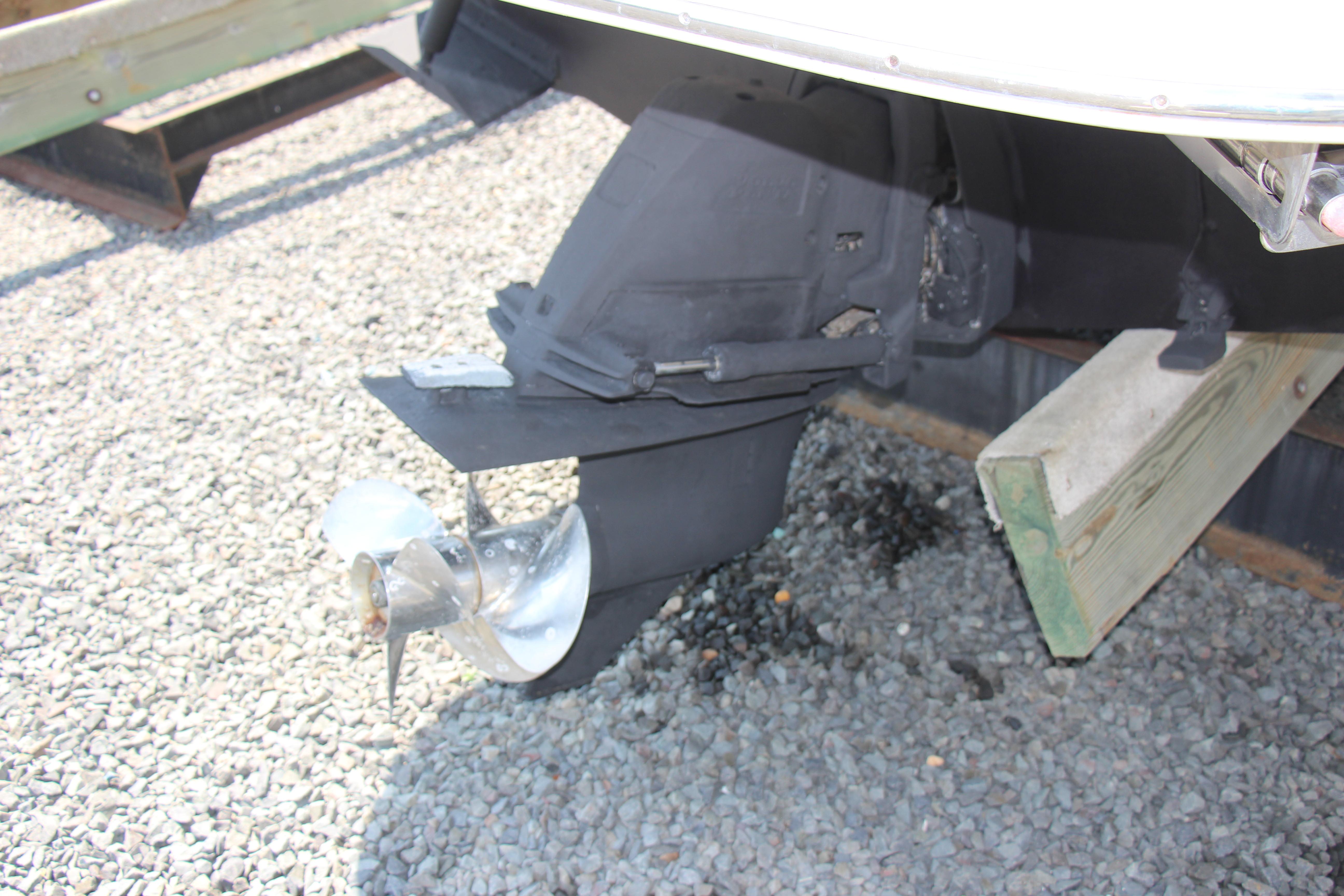 2008 Larson Cabrio 260 boat propeller and stern drive on gravel surface.