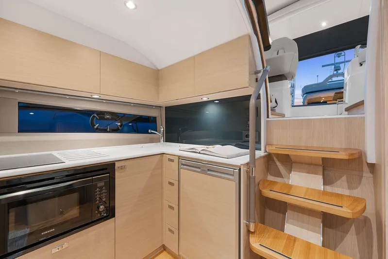 V40157 Yacht Photos Pics Modern kitchen interior of 2023 Princess V40 yacht with wooden cabinetry and sleek appliances.
