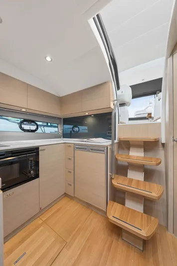 V40157 Yacht Photos Pics Modern kitchen interior of 2023 Princess V40 yacht with wooden stairs and sleek cabinetry.