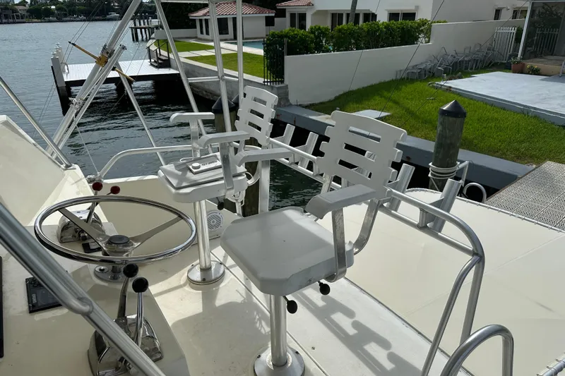  Yacht Photos Pics 1990 Viking 43 Convertible yacht helm with white captain chairs and steering wheel, docked by waterfront.