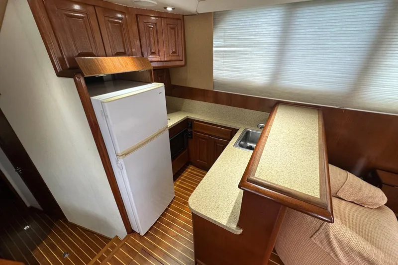  Yacht Photos Pics 1990 Viking 43 Convertible yacht kitchen with wood cabinets, countertop, and white refrigerator.
