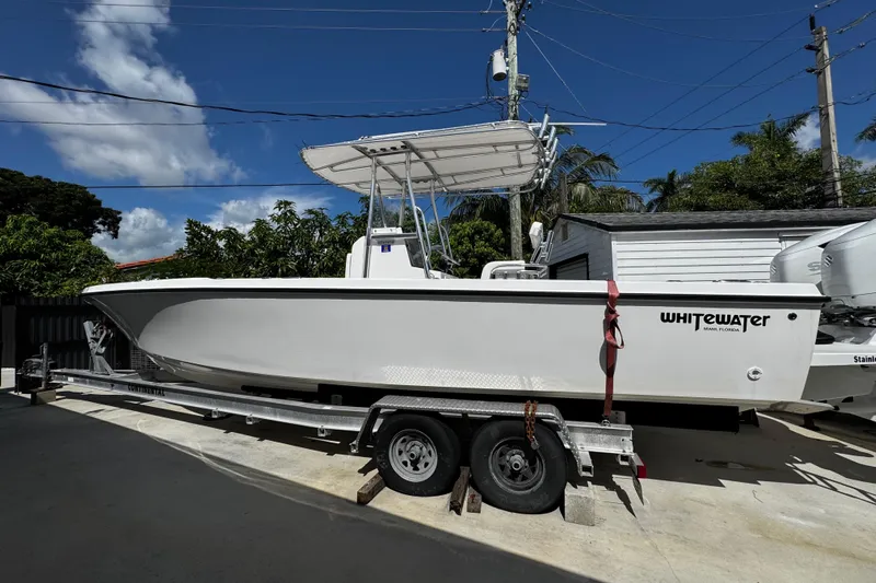  Yacht Photos Pics 2022 Whitewater 28 Open boat on trailer, parked outdoors under clear sky.