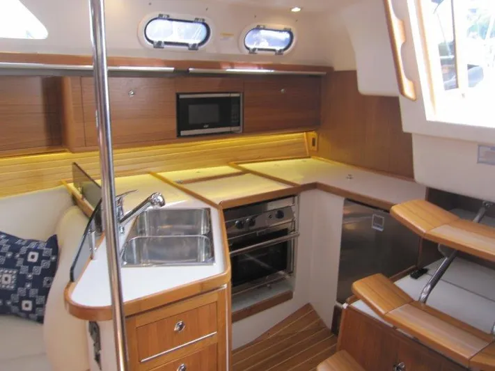 Hurkle Durkle Yacht Photos Pics 2024 Catalina 385 yacht interior kitchen with wood finish, sink, stove, and microwave.