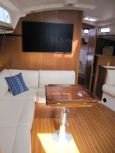 Hurkle Durkle Yacht Photos Pics 2024 Catalina 385 yacht interior with modern seating, wooden table, and mounted TV.