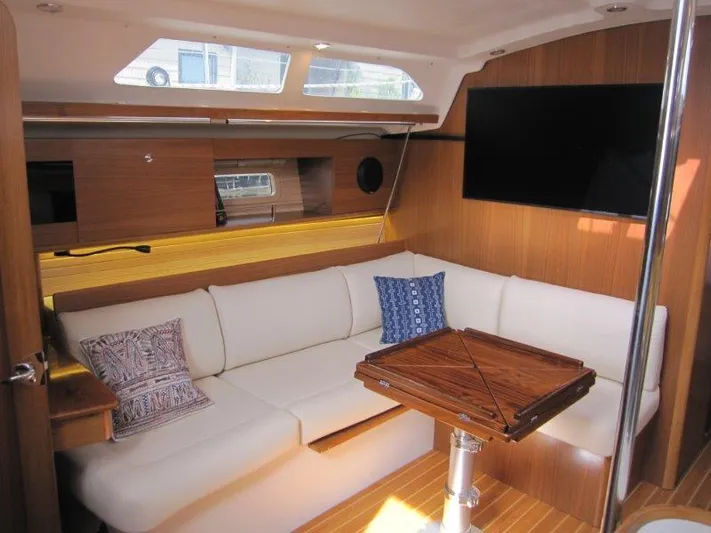 Hurkle Durkle Yacht Photos Pics 2024 Catalina 385 yacht interior with white seating, wooden table, and mounted TV.