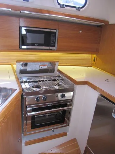 Hurkle Durkle Yacht Photos Pics 2024 Catalina 385 yacht kitchen with stove, oven, microwave, and wooden cabinetry.