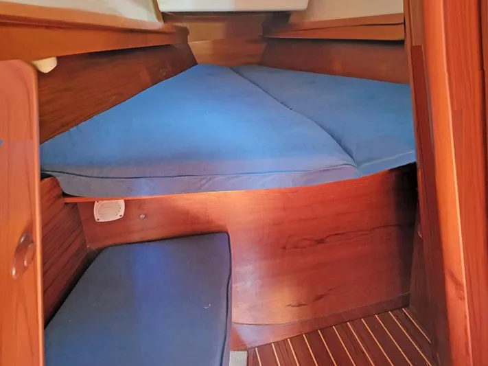 Yacht Photos Pics Cabin interior of 2000 Jeanneau Sun Odyssey 40 with blue cushions and wooden finish.