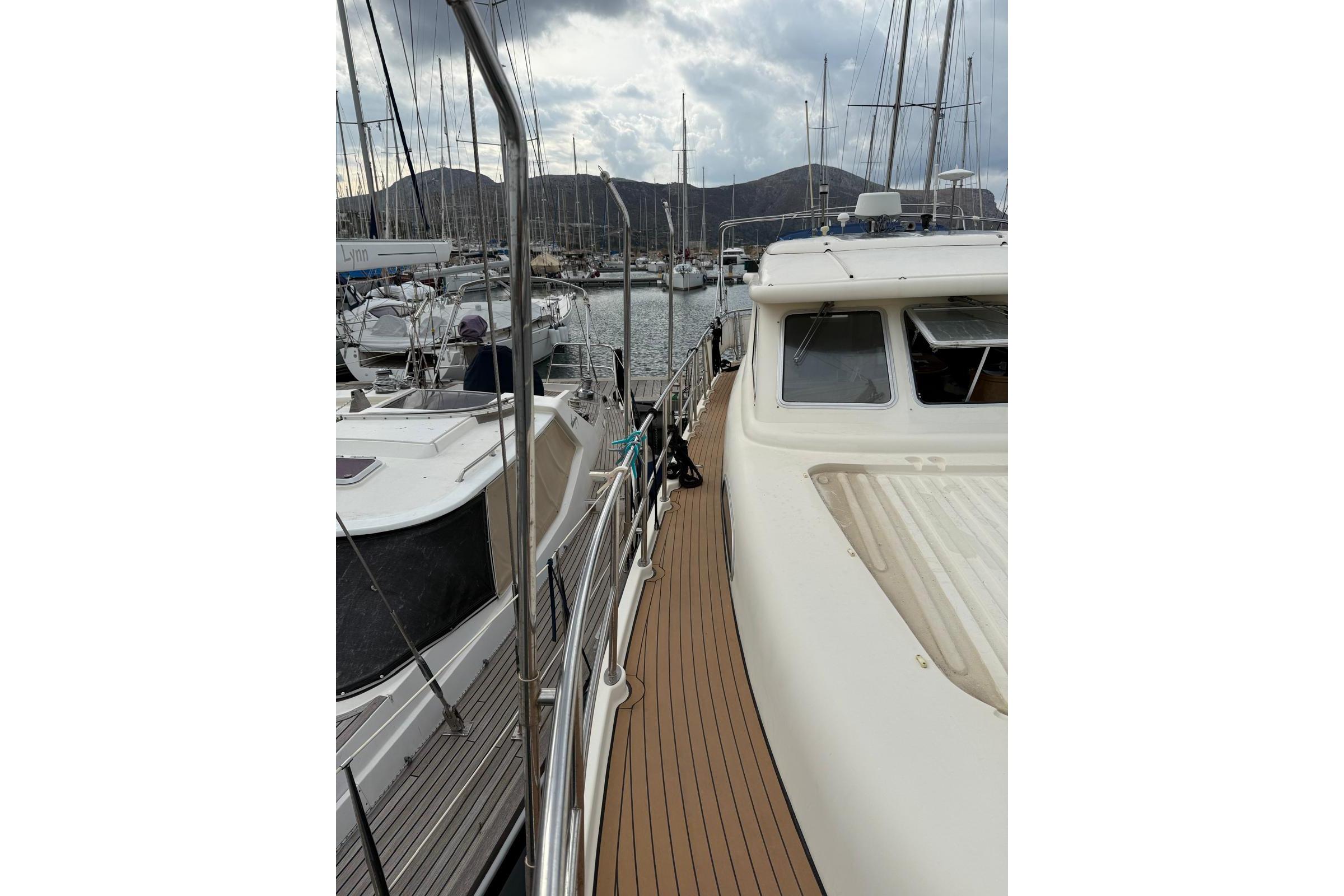 2000 Elling E3 yacht docked in a marina with surrounding boats and mountains.